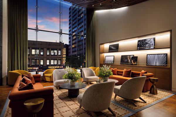A modern lounge with a city view, comfortable seating, and decorative plants.