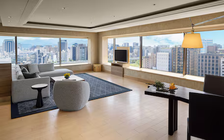 A spacious living room with a large window, a sofa, a coffee table, and a TV.