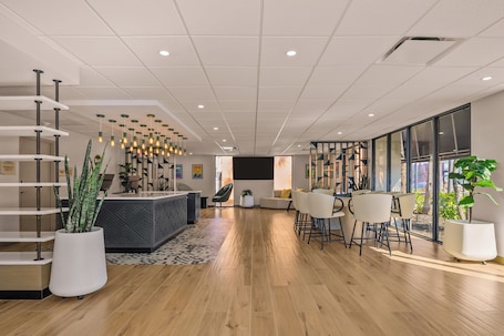 A modern reception area with a wooden floor, white reception desk, and a seating area with white chairs.
