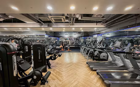A gym with cardio equipment, weight machines, and a mirrored wall.