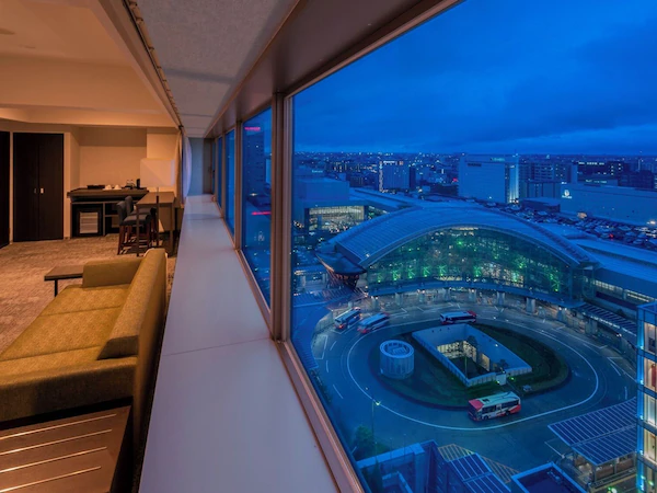A modern hotel room with a large window overlooking a cityscape and a roundabout.