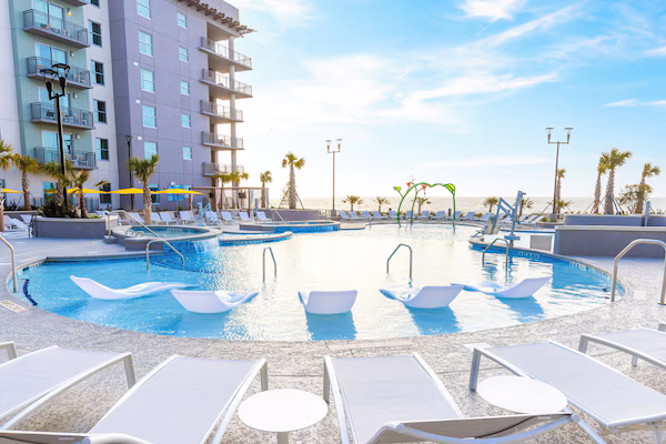 A pool area with multiple swimming pools, sun loungers, and umbrellas.