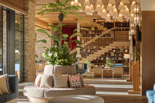 A modern interior with a staircase, a seating area with a plant, and a bookshelf.