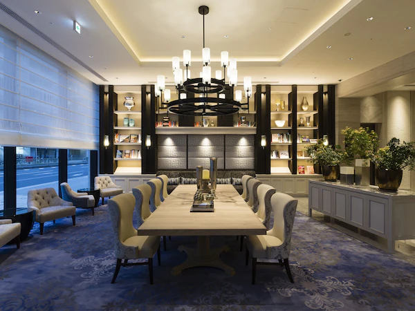 A spacious dining area with a long table, comfortable seating, and a decorative chandelier.
