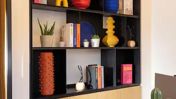 A modern room with a wooden cabinet, a black bookshelf, and a round table with a chair.