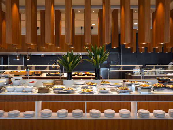 A buffet setup with various food items and a modern kitchen in the background.