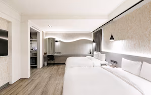 A modern hotel room with two beds, a desk, and a seating area.