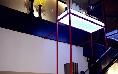 A modern interior with a staircase, a shelf with flowers, and a vase with flowers.