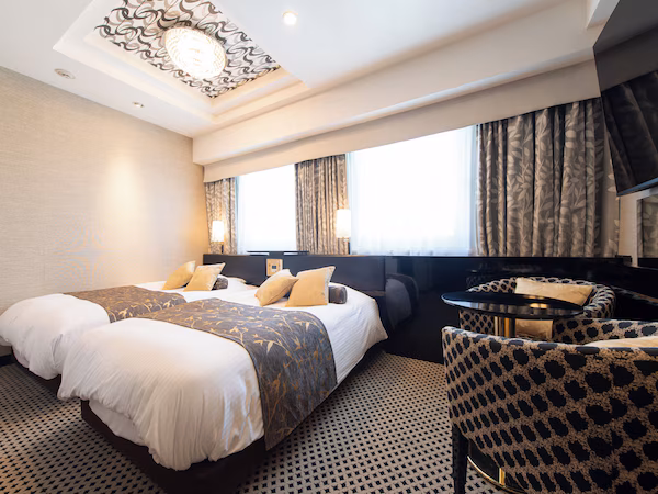 A hotel room with two beds, a sofa, a small table, and a TV.
