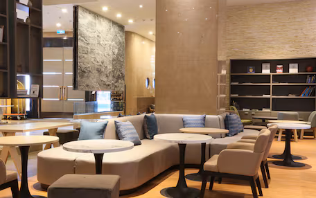 A modern lounge area with a curved sofa, round tables, and a bookshelf.
