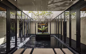 A modern building with glass doors and a central planter with a tree.
