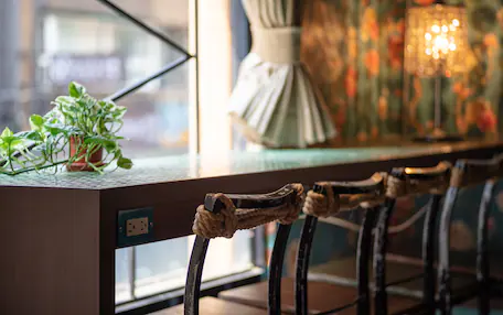 A bar area with a wooden counter, a potted plant, and a decorative lamp.