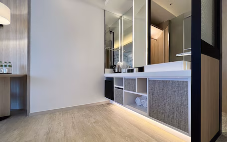 A modern bathroom with a wooden floor, a white vanity with a mirror, and a glass partition.