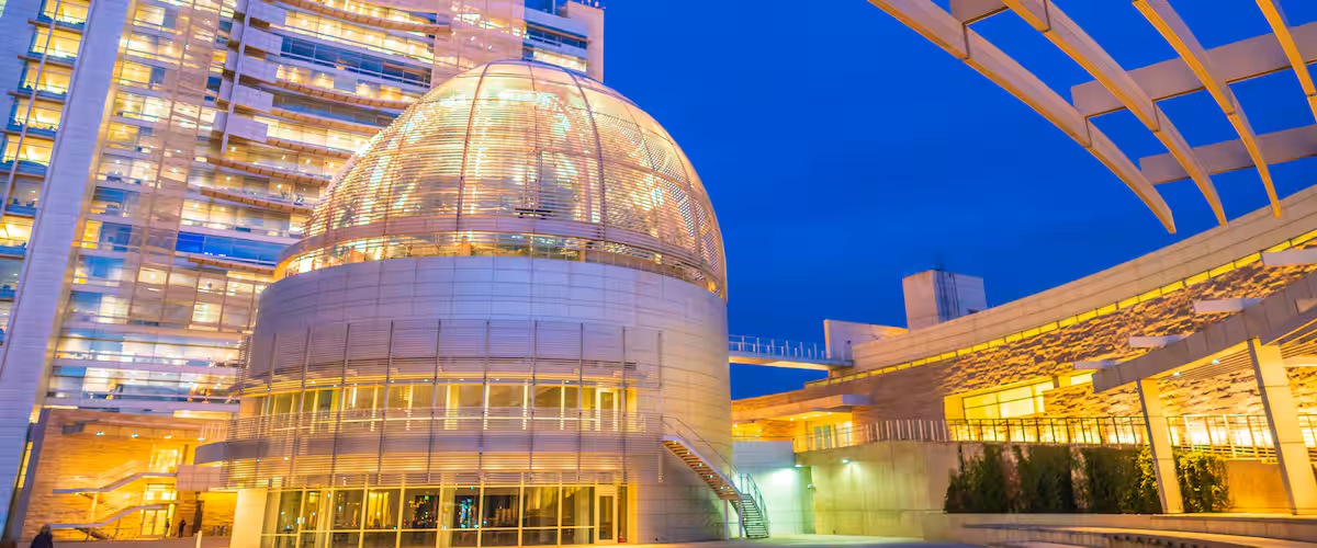 A modern building with a large dome and a glass facade.
