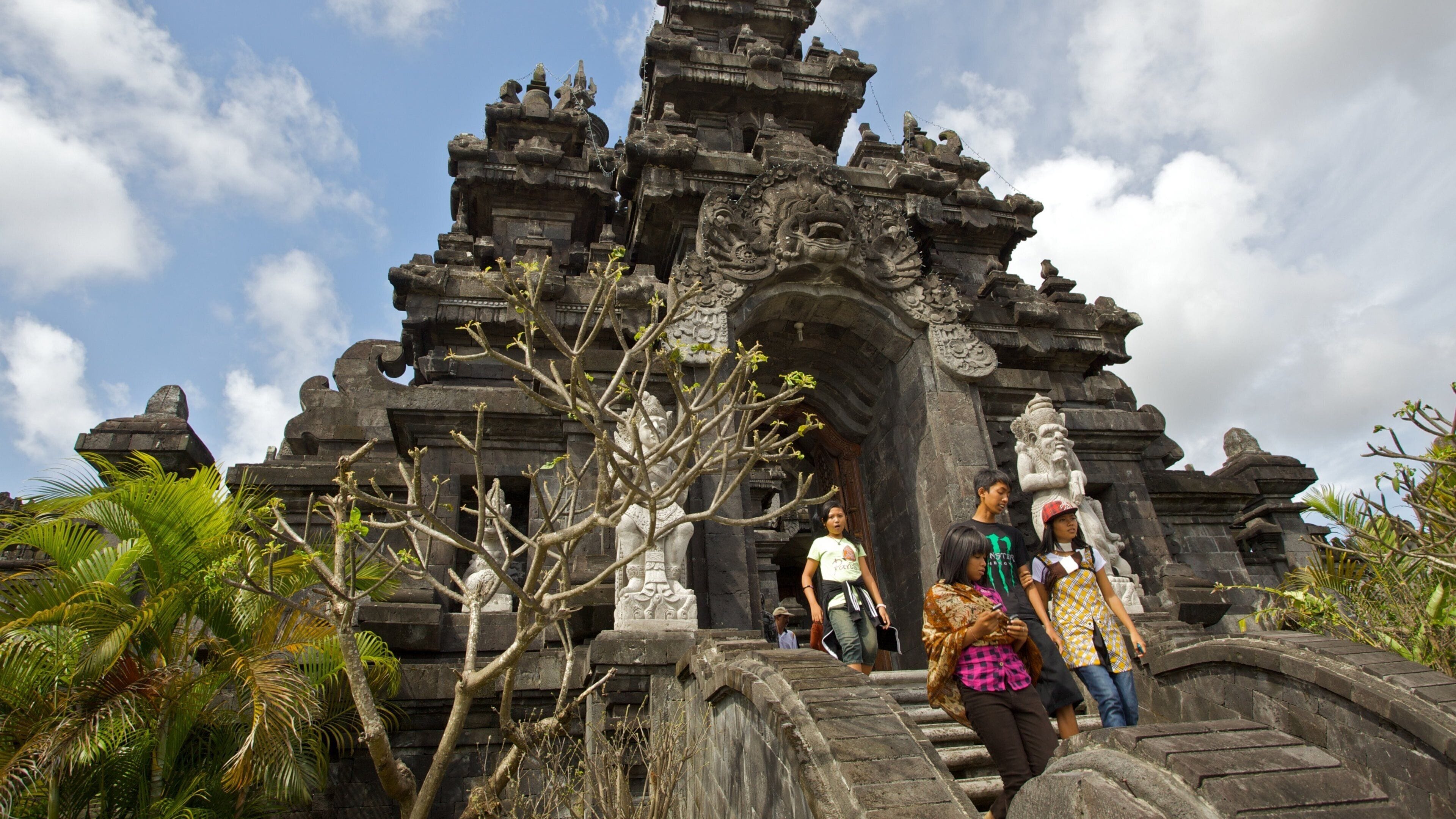 A temple entrance with intricate carvings and a stone bridge leading up to it.